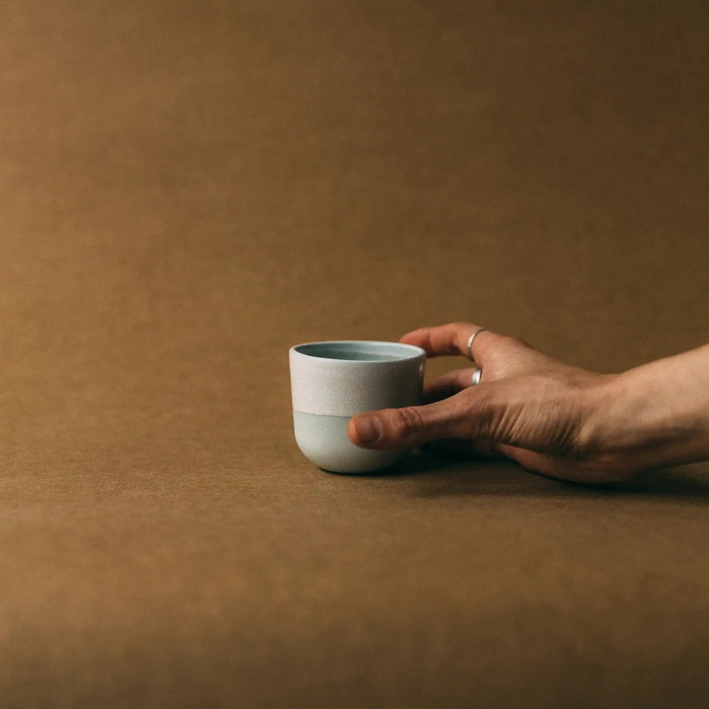 Dłoń trzyma czarkę ceramiczną FIGA 100ml - ujęcie z boku