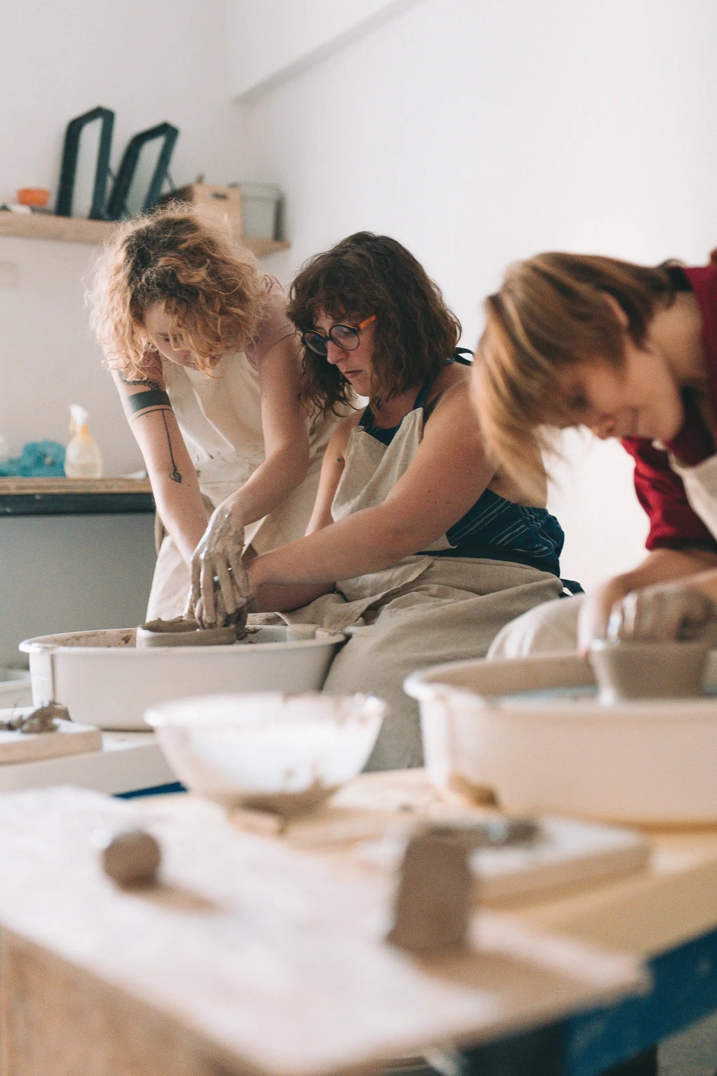 Grupa uczestniczek pracujących przy kołach garncarskich centrujących glinę podczas warsztatu - voucher Koło na start 1 spotkanie