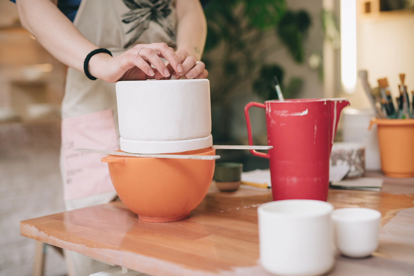 Dłonie, przygotowujące składniki na masę porcelanowa, nad pomarańczową miską