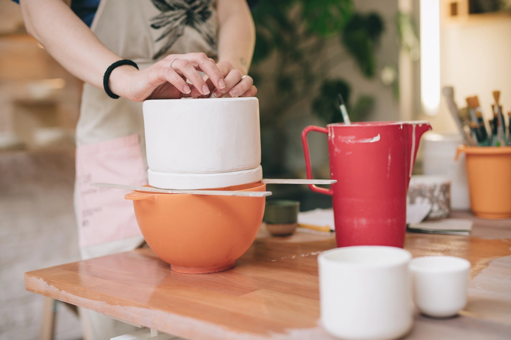 Dłonie, przygotowujące składniki na masę porcelanowa, nad pomarańczową miską