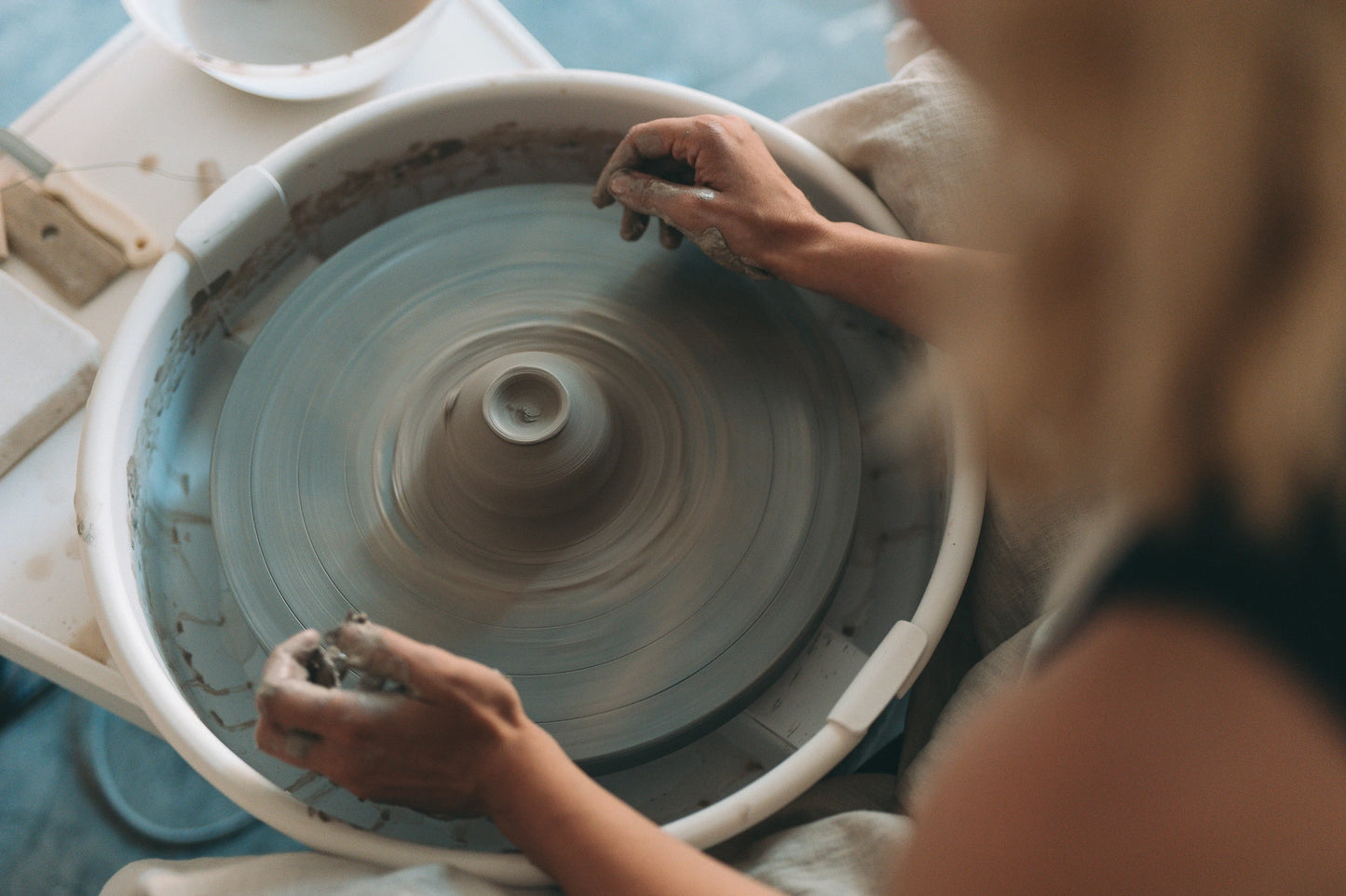 Ujęcie z góry jak ręce pracują nad formą na kole garncarskim