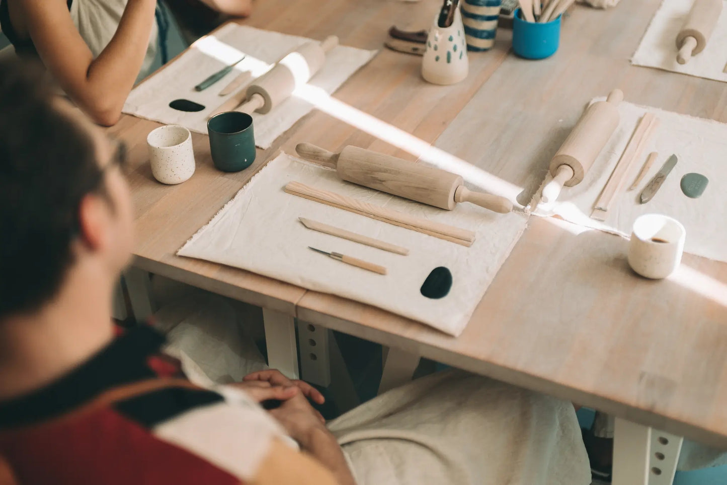 Ujęcie z góry na uczestniczka kursu ceramicznego siedzącego przy stole otoczonym narzędziami - voucher miesięczny kurs lepienia 4 spotkania