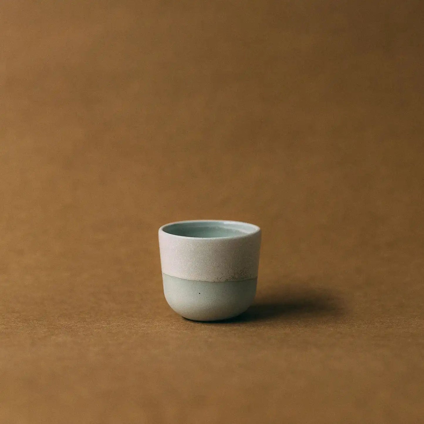 Czarka ceramiczna FIGA 100ml w kolorze szałwiowym na jasno brązowym tle