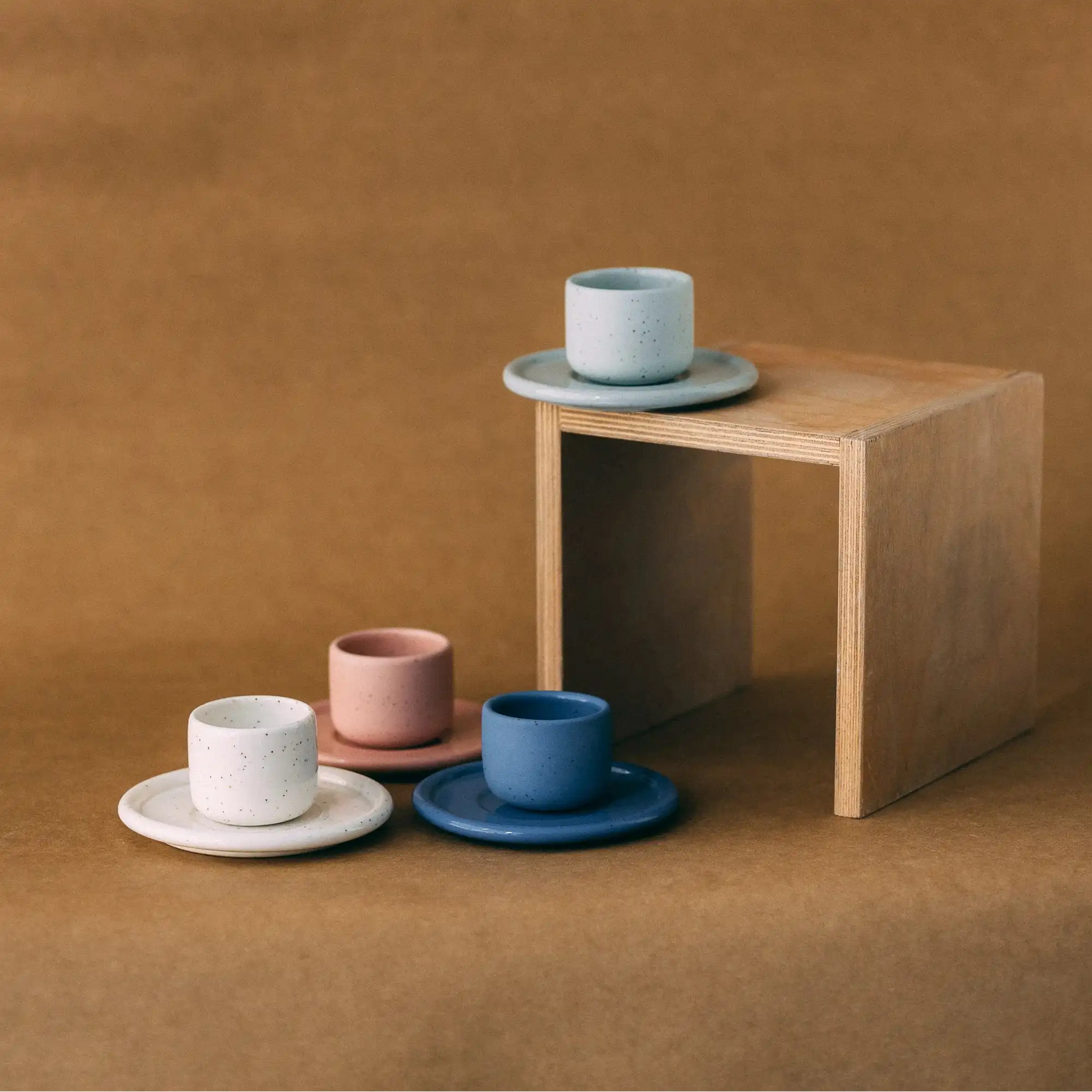 Kompozycja czterech czarek ceramicznych PopUp z podstawką na jasno brązowym tle