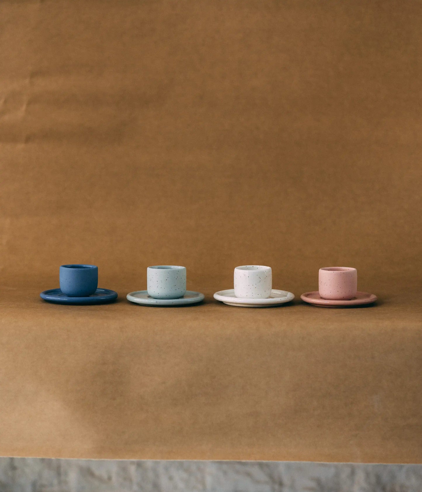 Cztery czarki ceramiczne PopUp z podstawką - ustawione w rzędzie na jasno brązowym tle