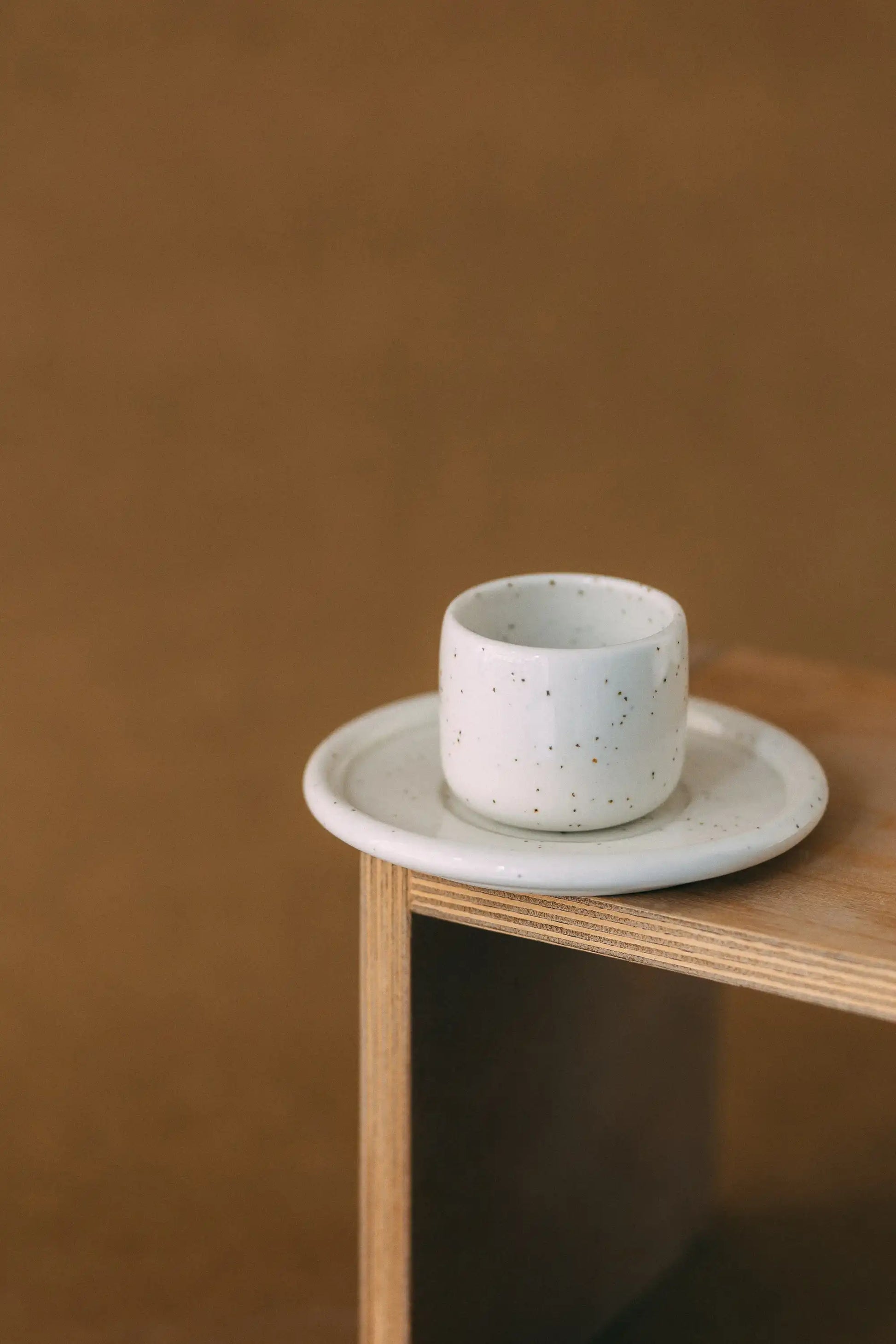 Czarka ceramiczna PopUp z podstawką w kolorze białym na jasno brązowym tle