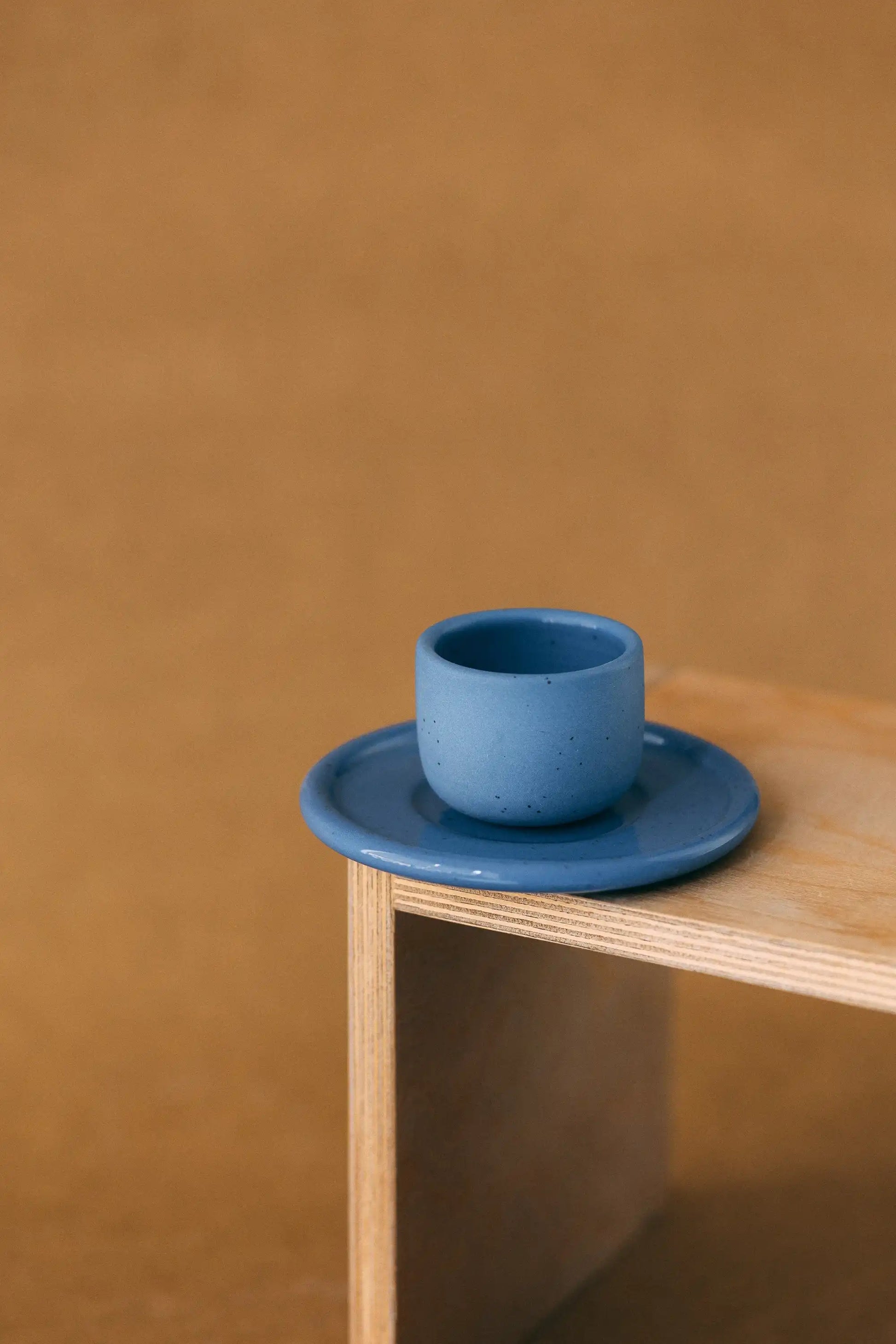 Czarka ceramiczna PopUp z podstawką w kolorze niebieskim na jasno brązowym tle