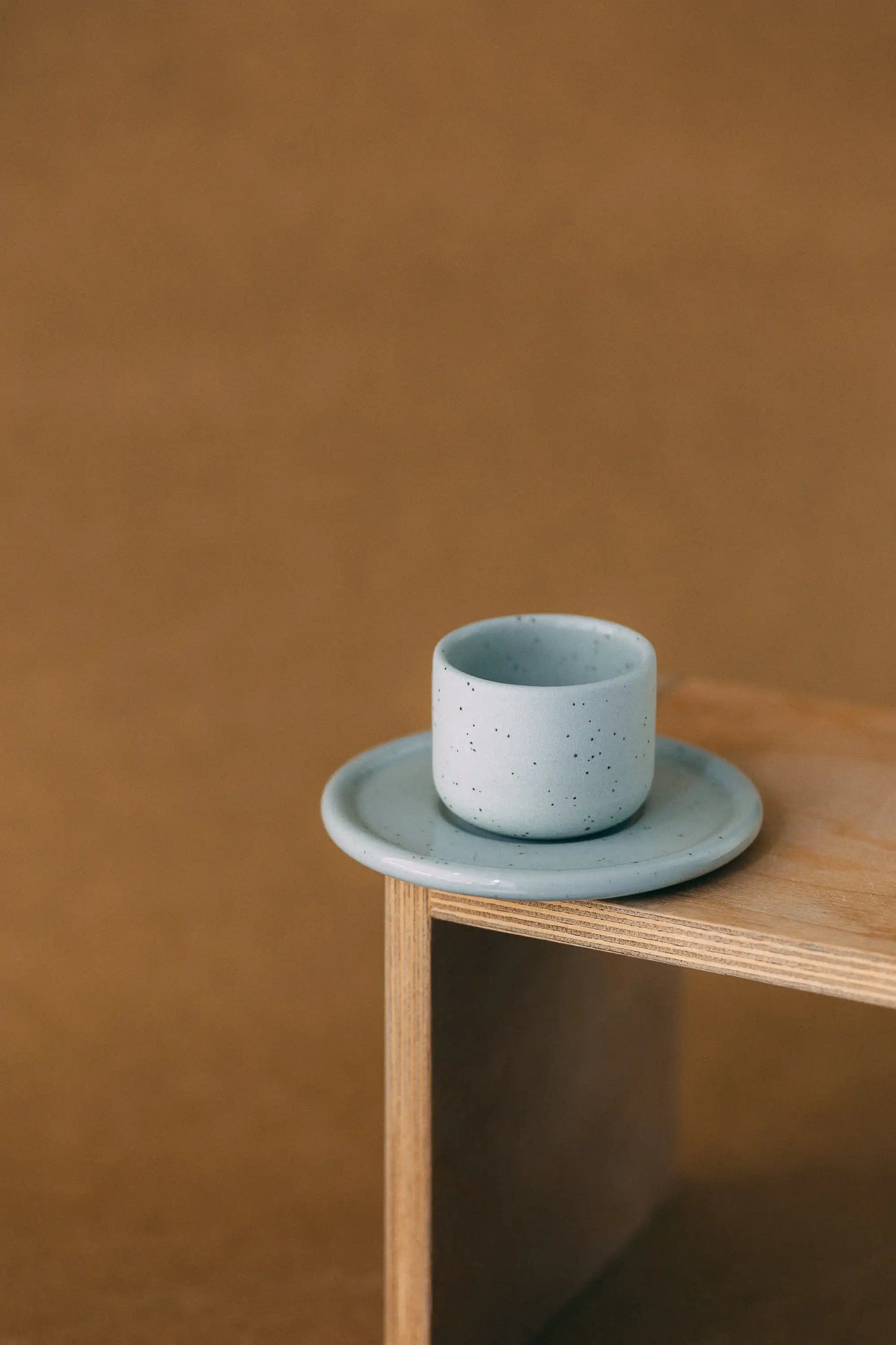 Czarka ceramiczna PopUp z podstawką w kolorze szałwiowym na jasno brązowym tle