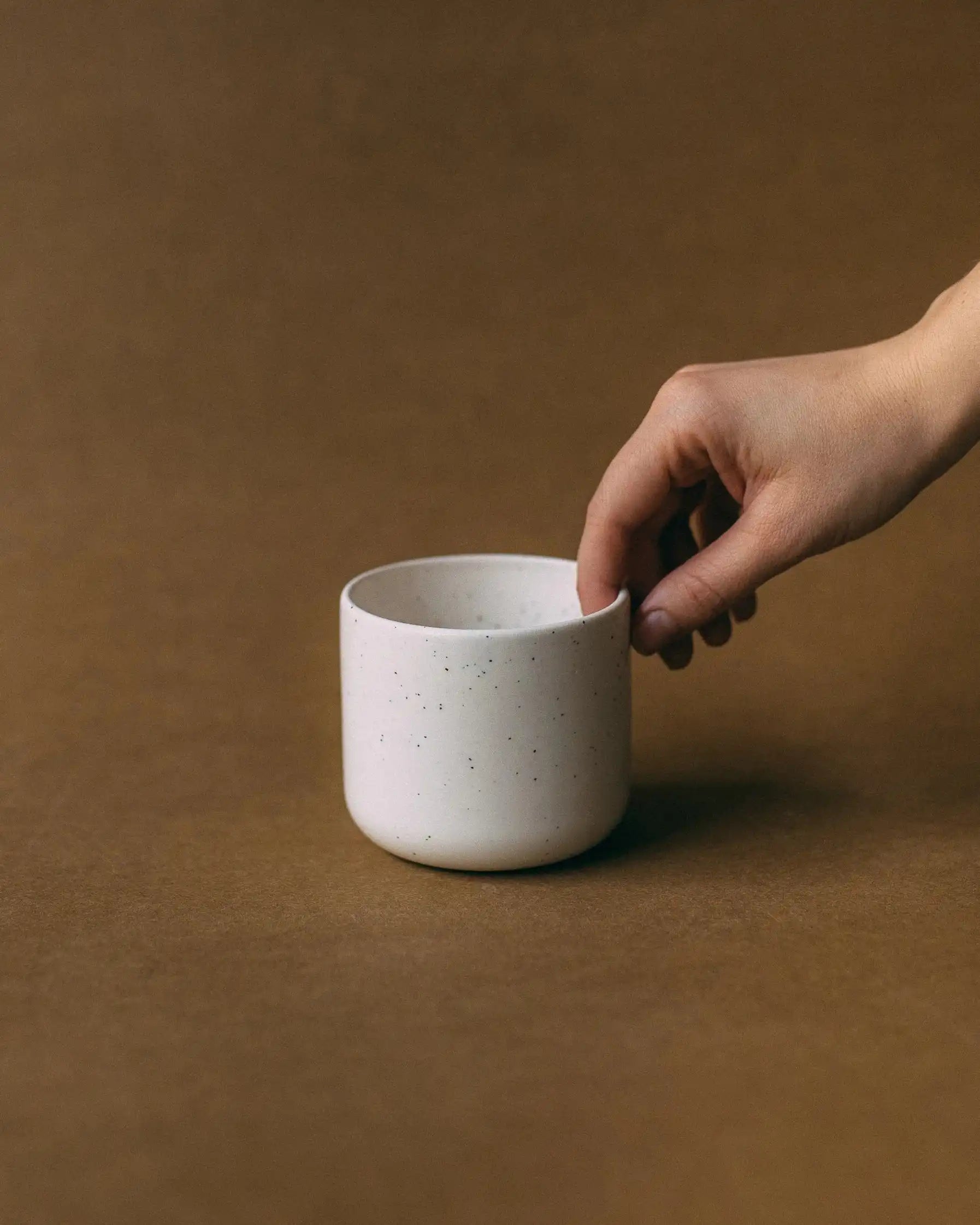 Dłoń trzymająca kubek ceramiczny TAP w kolorze białym