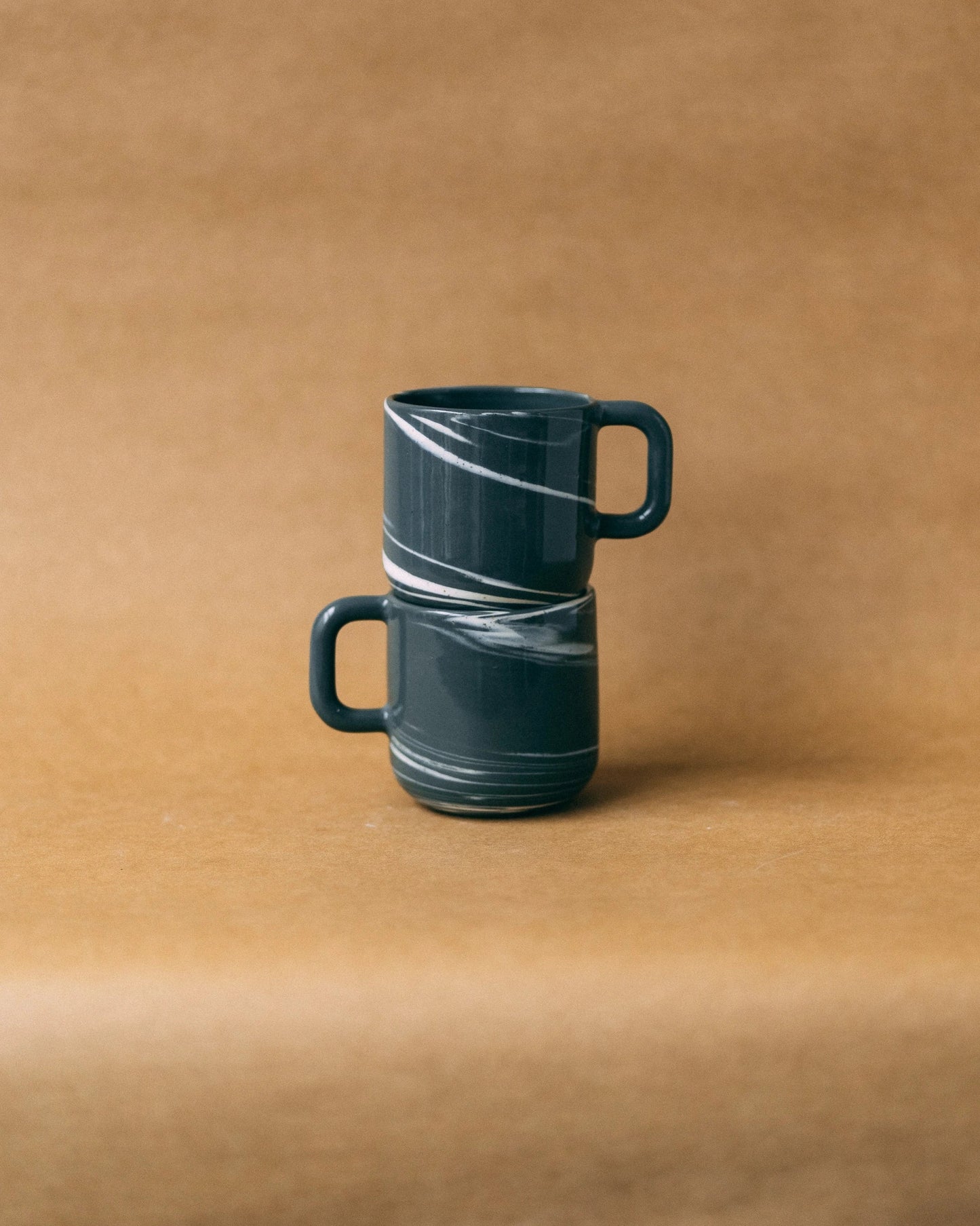 Dwa kubki ceramiczne z uchem Smog, ustawione jeden na drugim, z uchami zwróconymi w odwrotne strony - widok z boku