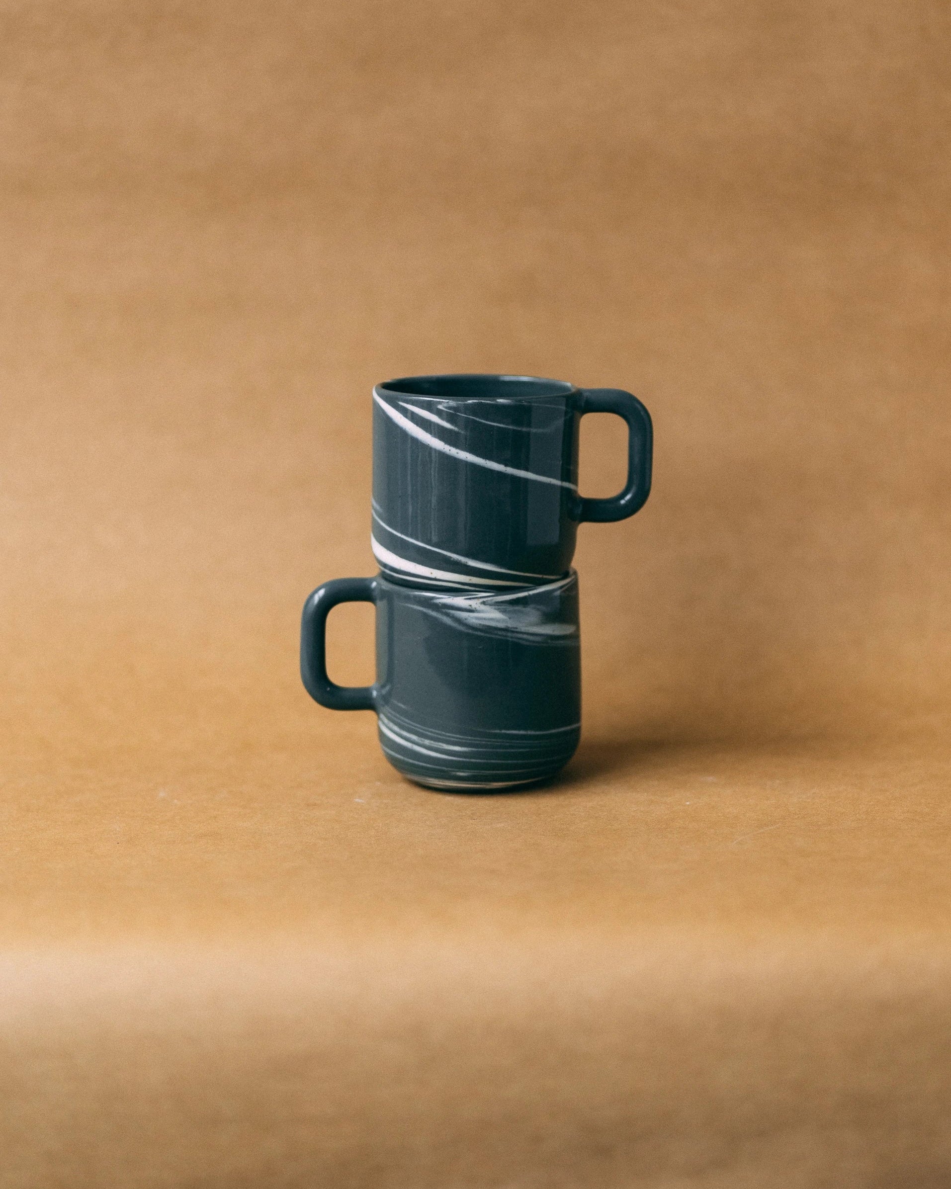 Dwa kubki ceramiczne z uchem Smog, ustawione jeden na drugim, z uchami zwróconymi w odwrotne strony - widok z boku