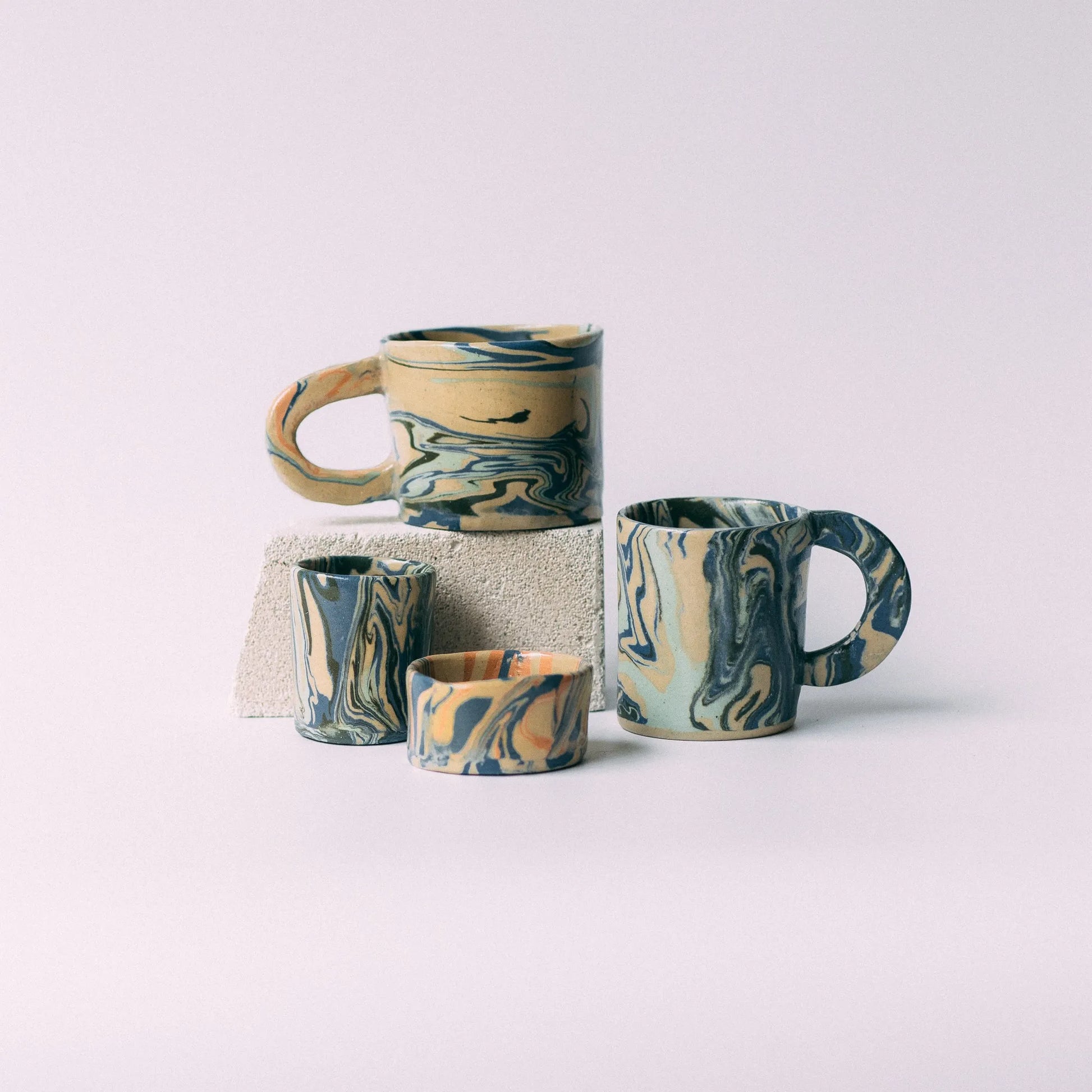 Kompozycja dwóch kubków z uchem i dwóch mniejszych, prostych naczyń wykonanych z połączenia czterech różnych mas barwionych