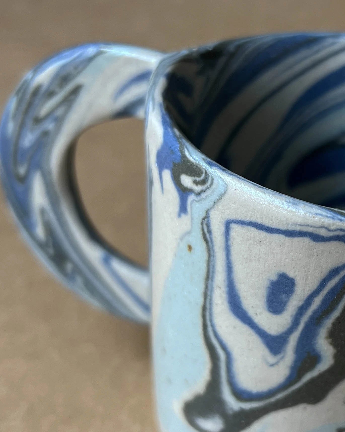 Fragment kubka wykonanego z kilku kolorowych mas, pomieszanych ze sobą organicznie