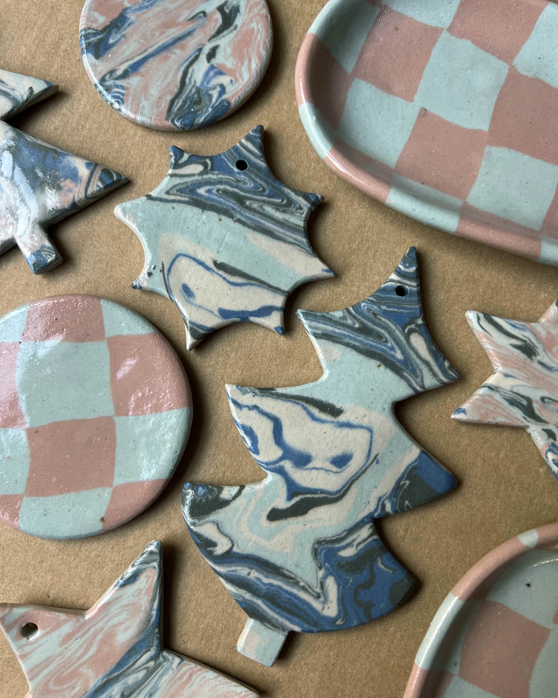 Zbiór ułożonych na płasko ceramicznych gwiazdek, choinek i kółek wykonanych z połączonych ze sobą kolorowych mas barwionych