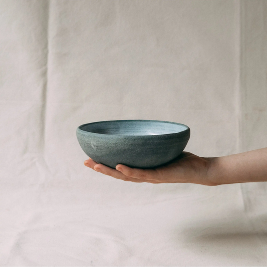 Dłoń trzyma ceramiczną miskę w kolorze ciemnego grafitu z matowym wykończeniem.