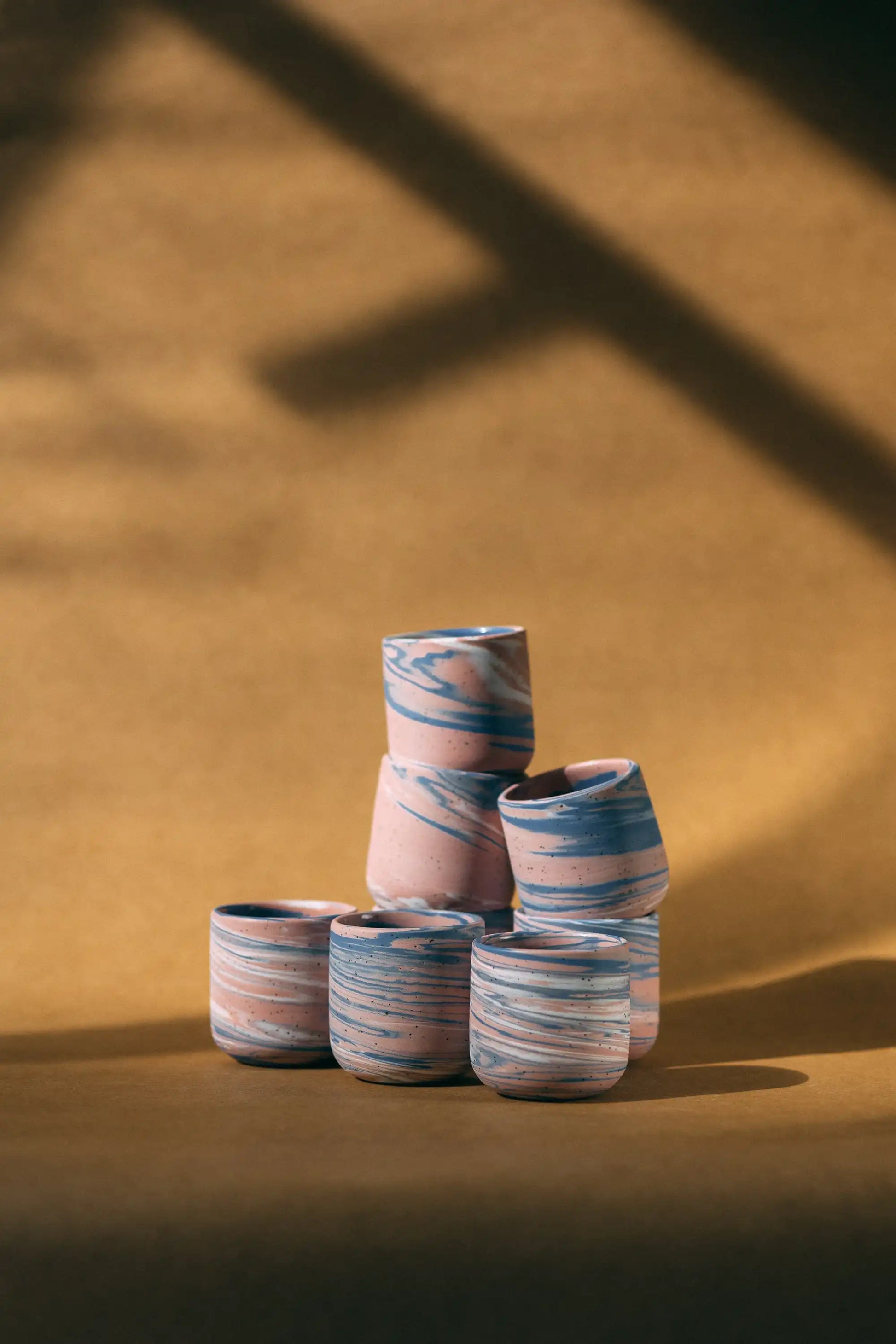 Kompozycja kilku czarek ceramicznych w marmurkowym kolorze różowym, białym i niebieskim