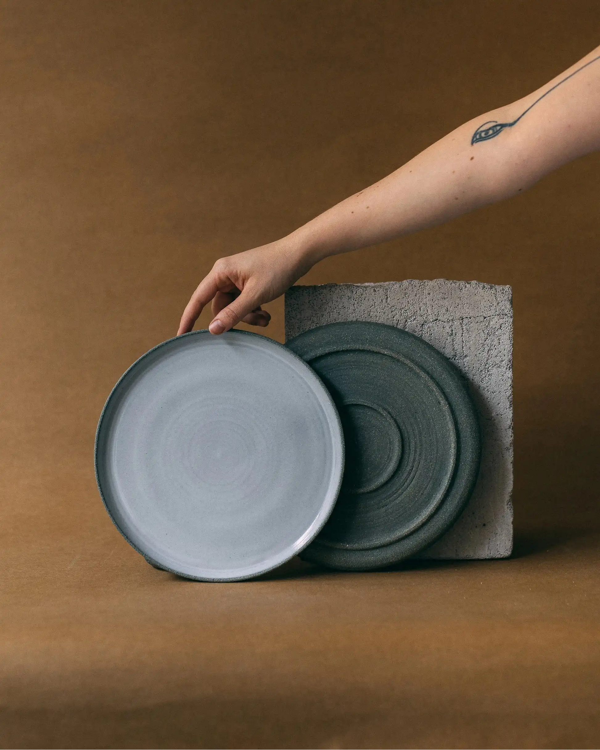 Ręka prezentująca talerze obiadowe ceramiczne w kolorze grafitowym - przód i tył