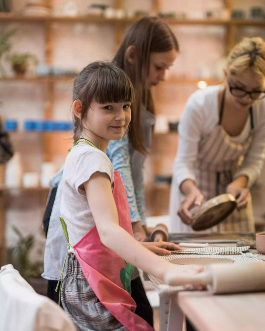 Uśmiechnięta dziewczynka stojąca przy stole, na którym odbywają się warsztaty